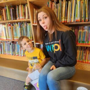 Young woman with preschool boy sticking tongues out