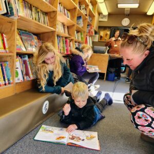 Young boy with sister and mother reading a book