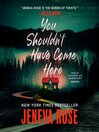 Cabin in the woods lit up by a red light. Book cover for You Shouldn't Have Come Here