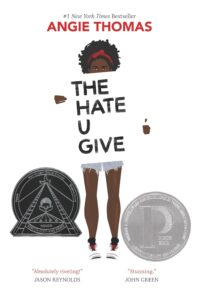 Black female teen holding a sign that reads "The Hate U Give"