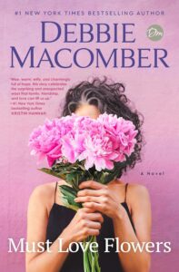 Woman with curly gray hair holding bouquet of pink peonies