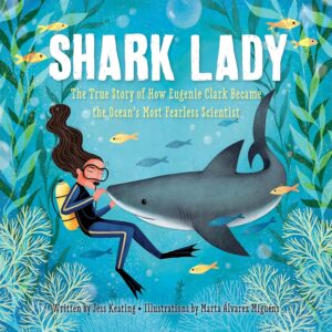 Woman wearing scuba gear and touching the nose of a great white shark