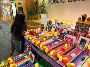 A young girl placing a photo of a lost loved one in the library's community ofrenda. 