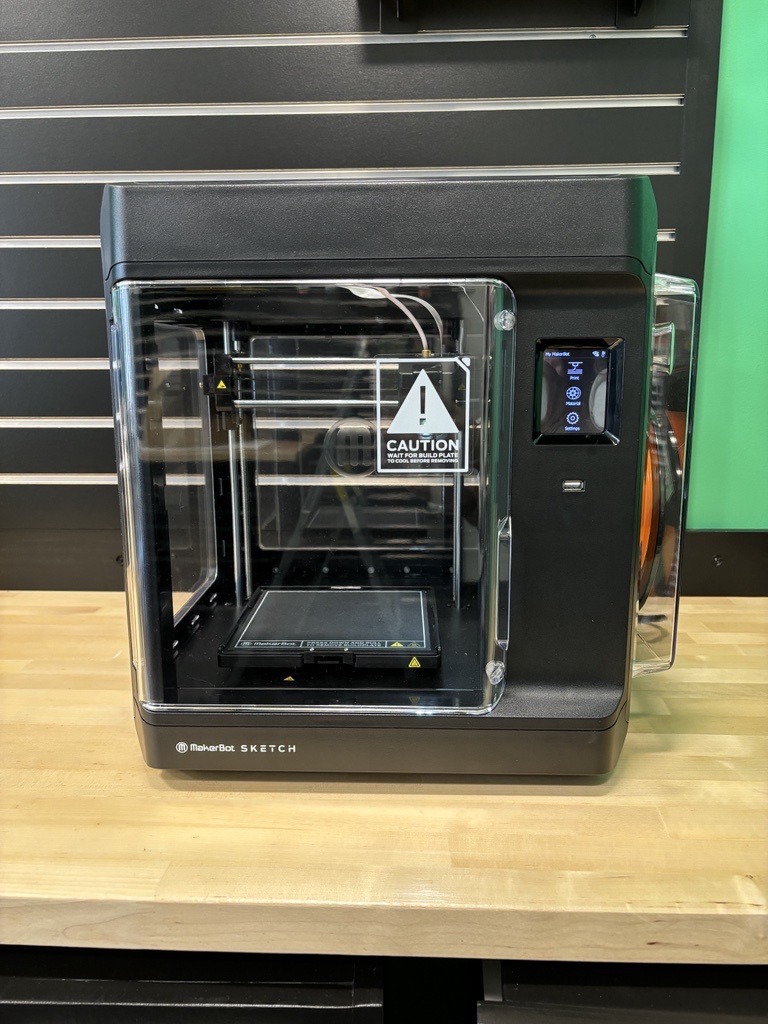 3D printer machine sitting on a wooden table.