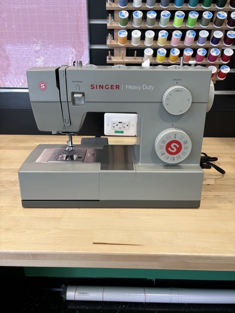 Gray sewing machine on wooden table.