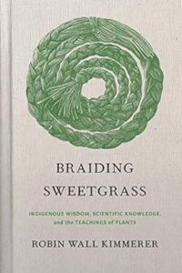 The cover of “Braiding Sweetgrass” by Robin Wall Kimmerer. A beige background with circle of green, braided sweetgrass in the center.  