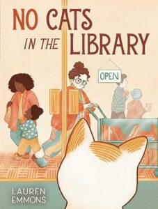 The cover of “No Cats in the Library” by Lauren Emmons. The back of the head of a white cat is shown in front of the sliding glass doors of a library where library patrons are pursuing books inside.  