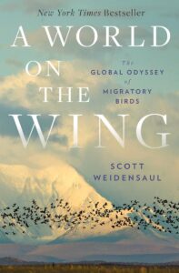 The cover of “A World on the Wing : The global odyssey of migratory birds” by Scott Weidensaul. A flock of black birds fly together in front of a grand mountain landscape. The snow covered mountain blended in with the clouded sky.