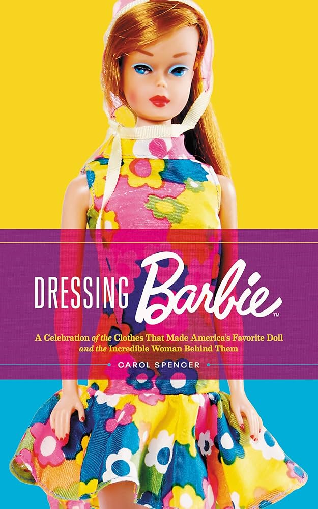 Book cover of Dressing Barbie by Carol Spencer. It features a vintage Barbie doll wearing a colorful floral dress with a full skirt, set against a split yellow and blue background. The title is in white letters across a translucent pink band, with the subtitle in smaller yellow text below.