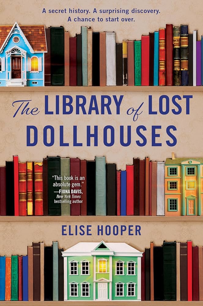 Book cover for Library of Lost Dollhouses. Three shelves of books can be seen with a blue dollhouse on the top shelf and green dollhouse mansion on the bottom.