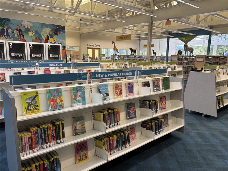 Multiple shelving units displaying popular adult, teen, and youth books.